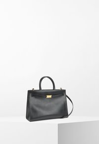 Svart läderhandväska med en strukturerad form, dubbla handtag, guldfärgad hårdvara och en framknäppning. Slät textur med en minimalistisk design.