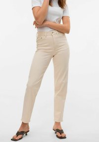 Beige høyt liv jeans med rett ben passform, med glidelås, fem lommer og synlige sømdetaljer. Glatt bomullsstoff.