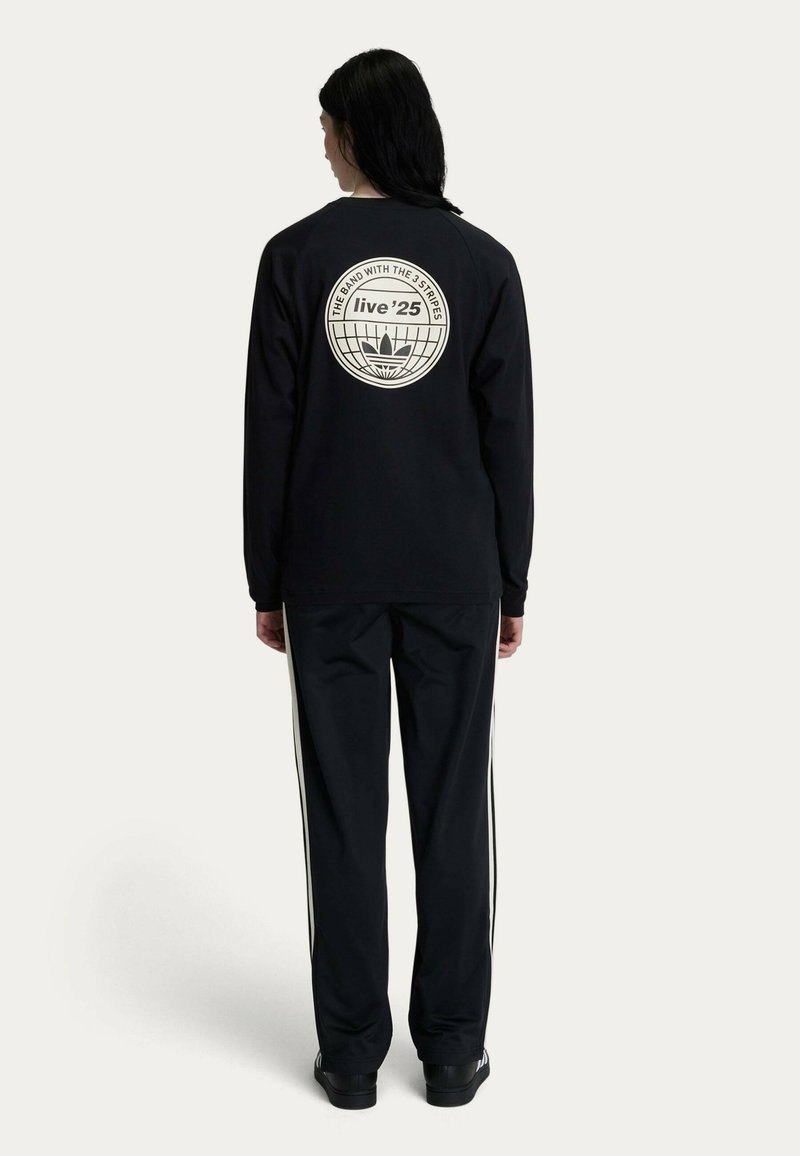 Black long-sleeve shirt with a circular white graphic on the back and black pants with white side stripes. Both items are casual wear.