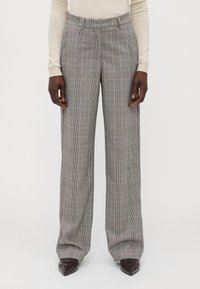 Pantaloni a quadri grigi con una vestibilità rilassata, caratterizzati da una vita alta, tasche laterali e una superficie del tessuto liscia. Accentuati da sottili linee colorate.