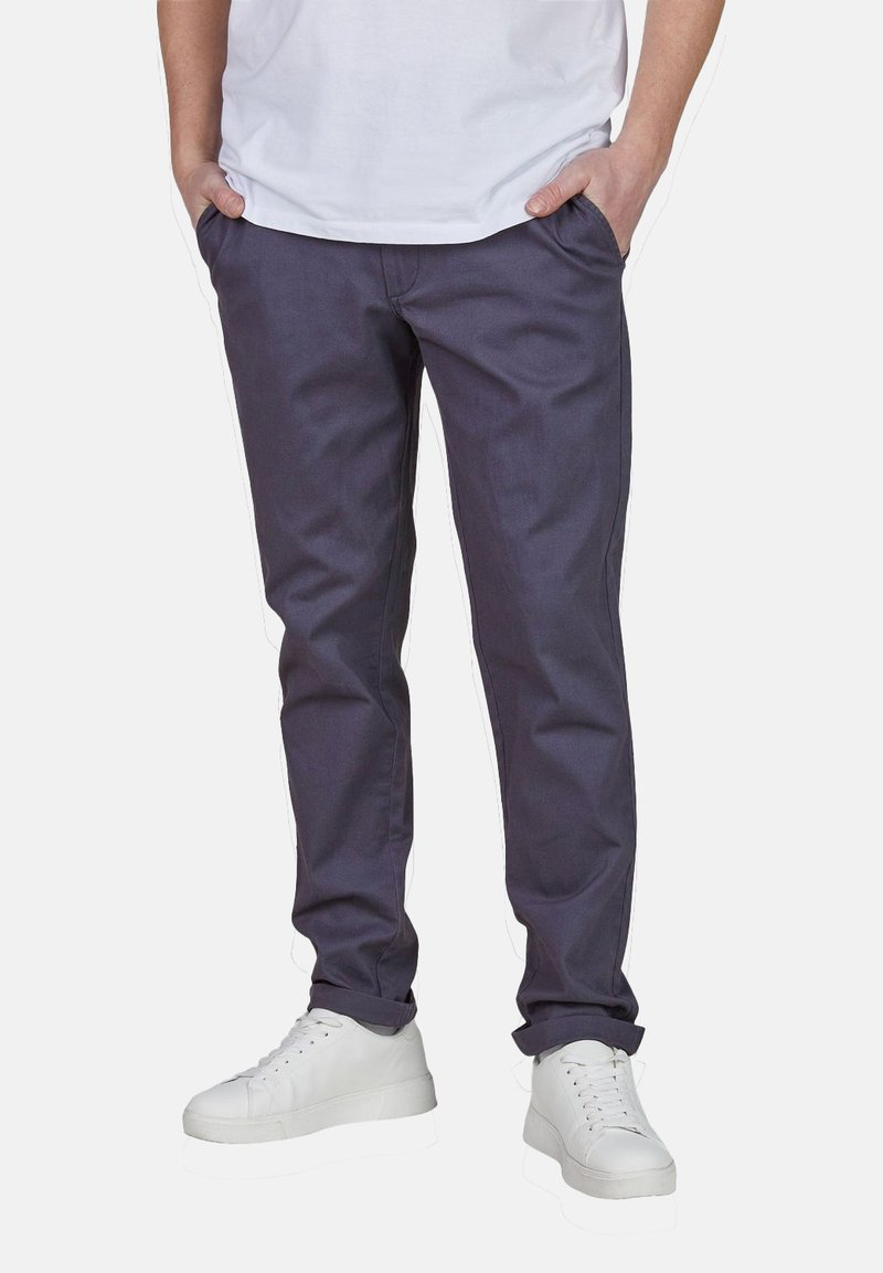 Slim-fit dunkelgraue Pants aus einem Baumwoll-Mischgewebe, mit Seitentaschen und glatter Textur, kombiniert mit weißen Sneakers.