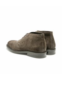 Bottes courtes en daim brun avec un bout arrondi, quatre œillets, et une semelle en caoutchouc ; texture lisse et détails de couture minimalistes.