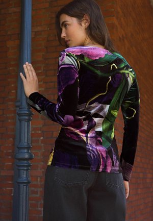 Figurbetontes Langarmshirt aus schwarzem Samt mit einem bunten Blumenmuster. Verfügt über einen runden Halsausschnitt und subtile Texturen, kombiniert mit dunklen Hosen.