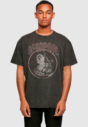 T-shirt en coton noir avec une illustration de Deadpool, entourée d'un cadre rouge rond et avec une finition usée, à manches courtes et coupe décontractée.