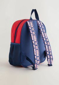 Mochila roja y azul marino con bolsillo lateral de malla, correas acolchadas con el texto "¡SPIDEY GO!" y un diseño curvado y estructurado.