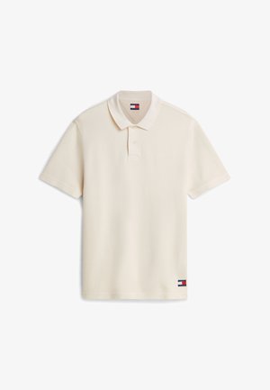 Lühikeste varrukatega kreemjas tekstuuriga polomees, millel on krae ja kaks nuppu, ning väike punase, valge ja sinise värviga Tommy Hilfigeri logo plaastri serval.