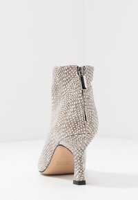 Textured snake-print ankle boot in off-white and gray. Features a fitted silhouette and a zip closure at the back with a stiletto heel.