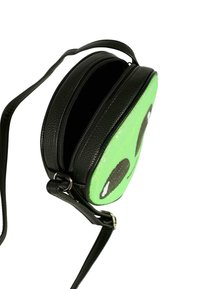 Piccolo borsello nero rotondo a tracolla con un design di faccia di alieno verde scintillante e un compartimento con zip aperto.