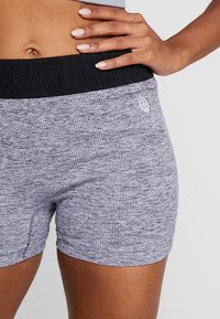 Šedé texturované atletické šortky s černým elastickým pasem a subtilním brandingem na boku. Navrženy pro pohodlí a pohyblivost.
