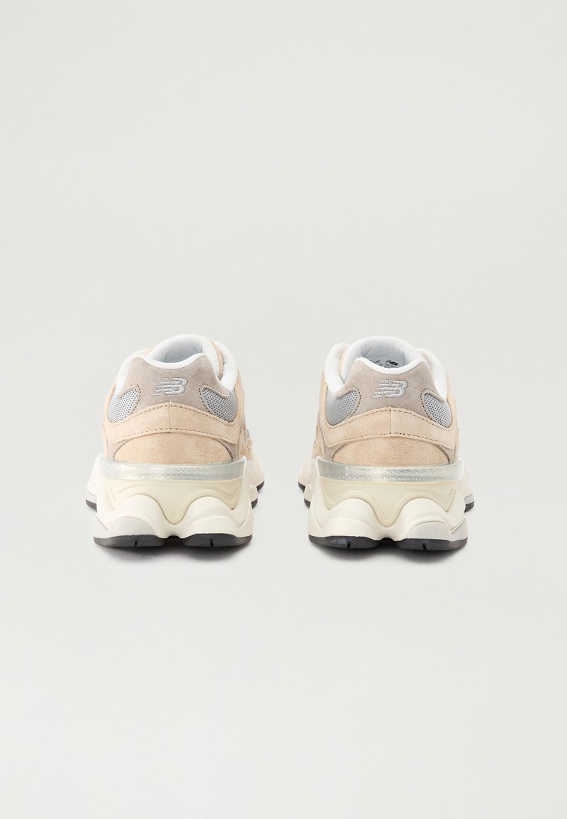 Beige Wildledersneaker mit weißen Mesh-Elementen und grauen Details. Verfügt über eine gepolsterte, strukturierte Sohle und eine reflektierende Ferse.