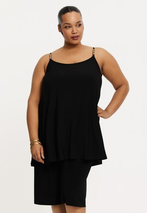 Schwarzes ärmelloses Oberteil mit verstellbaren Trägern, ausgestattet mit dekorativer Hardware. Leichter Stoff fällt hüftlang und wird mit passenden Shorts kombiniert.