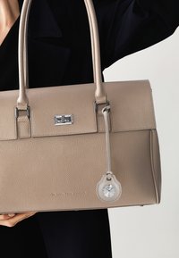 Borsa a mano in pelle beige con finitura texturizzata, hardware in argento e ciondolo orologio staccabile. Forma rettangolare e manici doppi.