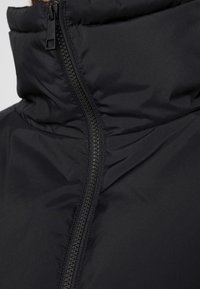 Close-up of a black puffer jacket zipper running vertically through the middle of the high collar area.