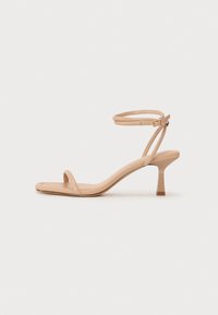 Sandales à talons hauts beige avec un bout carré, de fines sangles à la cheville et un design épuré et minimaliste. Texture lisse et talon bloc.