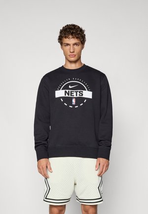 Sorte sweatshirt lavet af bomuldsblanding, med et hvidt grafisk logo og tekst. Accompanjeret af lyse, perforerede sportsshorts med sorte accenter.
