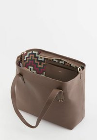 Bolso tote de cuero marrón con superficie texturizada, con un interior colorido de patrón en zigzag. Incluye un bolsillo con cremallera y asas resistentes.