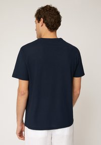 T-shirt in cotone blu navy con maniche corte, colletto girocollo e una vestibilità comoda. Texture liscia senza motivi o dettagli visibili.