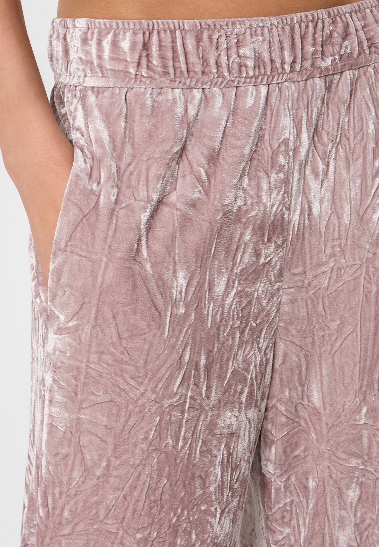 Welurówki w kolorze przybrudzonego różu, z marszczoną teksturą, elastycznym paskiem w talii i bocznymi kieszeniami. Miękki materiał o subtelnym połysku.