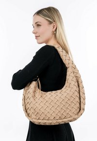 Woven beige handbag with a soft, textured surface and a large crescent shape, featuring a wide strap and a spacious interior.