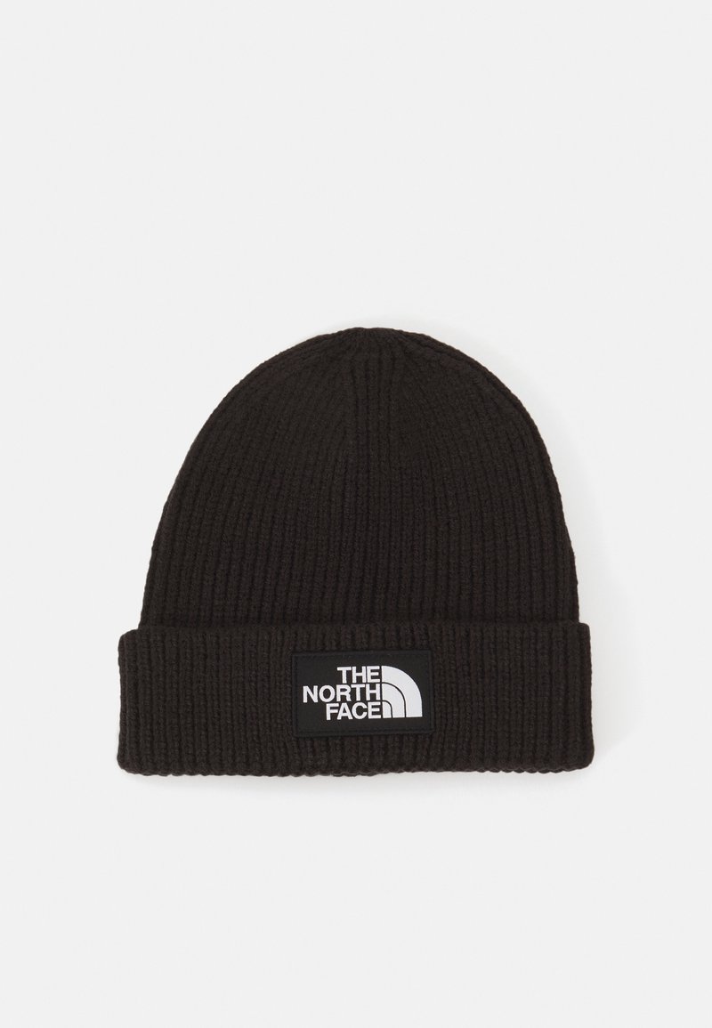 Gorro de punto negro con textura acanalada, que presenta un dobladillo y una etiqueta de logo blanca en la parte frontal.