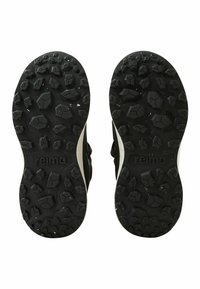 Czarne gumowe podeszwy butów z teksturowanym wzorem antypoślizgowym z sześciokątnymi kształtami i wytłoczonym logo "reima" po bokach.