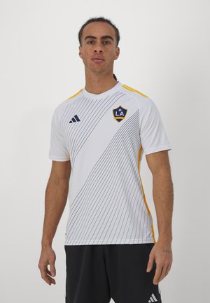 Camiseta de fútbol blanca de manga corta con rayas diagonales, acentos amarillos y el escudo de LA Galaxy. Fabricada en un material ligero y con cuello redondo.