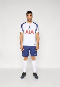 „Tottenham Hotspur“ futbolo apranga balta ir tamsiai mėlyna spalvomis. Antkainio matosi ryškus raudonas logotipas „AIA“, klubo ženklas ir „Nike“ ženklinimas. Trumpomis rankovėmis ir šortais.