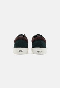 Niske tenisice koje sadrže kombinaciju zelenih i smeđih suede materijala, bele gumene potplate i Vans logo na peti.