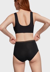 Ensemble de bralette noire et de culotte taille haute en tissu lisse, avec des bretelles larges et une finition en dentelle à la taille.