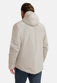 Giacca a cappuccio grigio chiaro in un materiale liscio e leggero. Presenta polsini elasticizzati e una zip frontale, con una vestibilità rilassata e leggermente allungata.
