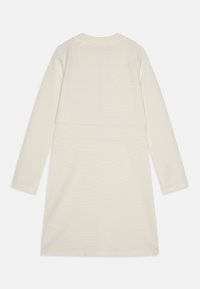 Langermet kjole i knelengde i off-white teksturert stoff, med innsvingt liv og rund hals. Enkel, ren design uten dekorasjoner.