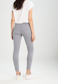 Grijze skinny jeans met een soepel textuur en achterzakken, gecombineerd met een wit T-shirt met korte mouwen en witte sneakers.