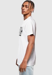 White cotton t-shirt featuring a graphic printed on the front. Standard fit with short sleeves and round neckline, smooth fabric texture.