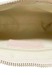 Rosa tygpåse med en mjuk insida, metalldragkedja och liten etikett. Texturen är mjuk och designen är enkel och funktionell.