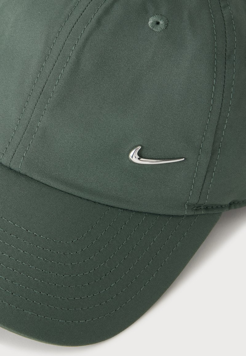 Grüne Baseballkappe mit aufgenähten Paneelen und kleinem silbernem Nike-Swoosh-Logo auf der rechten Vorderseite.