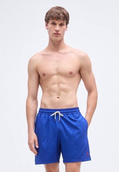Mėlyni maudymosi šortai su elastinga juosmens juosta, reguliuojamu raišteliu ir mažu raudonu logotipo detaliu kairėje kojoje, pagaminti iš lengvos medžiagos.