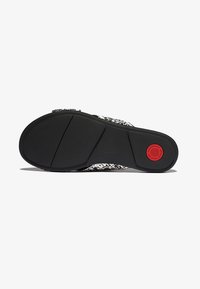 Zwarte zool met een gestructureerde grip; witte bovenkant met een geweven patroon. Rode accentlabel op de zool. Schoen ontworpen voor comfort en duurzaamheid.