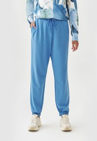 Helle blaue Jogginghose aus weichem Stoff, mit einem elastischen Taillenbund und Kordelzug, seitlichen Taschen und schmal zulaufenden Bündchen.