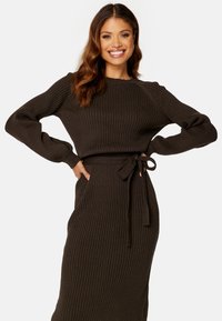 Abito a maniche lunghe a coste in marrone scuro, con silhouette aderente, cintura in vita e morbido tessuto a maglia caratterizzato da sottili linee verticali.
