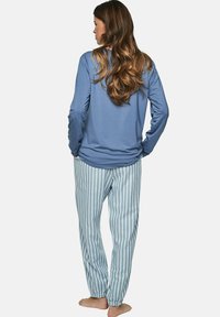 Un haut bleu à manches longues avec un col rond associé à un pantalon de pyjama rayé bleu clair. Le tissu semble doux et a une coupe décontractée.