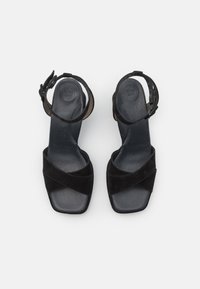 Černé semišové sandály na vysokém podpatku se čtveratou špičkou, zkříženými popruhy a nártním páskem, s polstrovanou stélkou označenou „SUPER SOFT.“