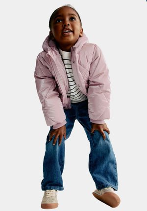 Chaqueta acolchada rosa claro con capucha, cierre de cremallera y puños acanalados, combinada con una camiseta a rayas y jeans azules. Zapatillas crema con suelas marrones.