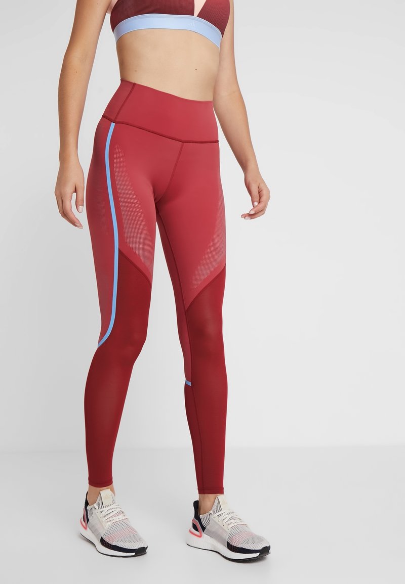 Røde atletiske leggings med høj talje, blå sidde accenter og mesh-detaljer. Materialet er glat, strækbart og tætsiddende til aktivt brug.