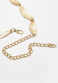 Collana in metallo dorato con collegamenti a forma di foglia texture, dotata di chiusura a molla e catena aggiuntiva per regolare la lunghezza.