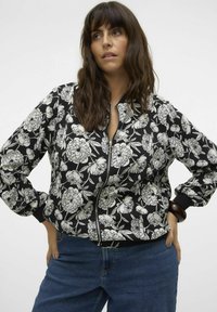 Chaqueta bomber floral en blanco y negro, con cierre de cremallera, puños acanalados y un ajuste oversize con patrones florales en toda la prenda.