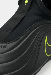 Μαύρο αθλητικό παπούτσι με λείο συνθετικό επάνω μέρος, που διαθέτει μια υφή με κυματιστό σχέδιο και έναν έντονο νεον πράσινο λογότυπο.