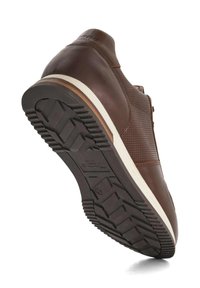 Brown leather shoe with a textured upper and light-colored rubber sole featuring a patterned tread for grip.