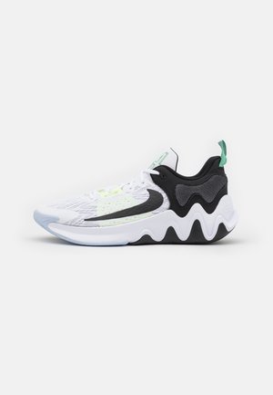 Zapatilla deportiva blanca y negra con una suela ondulada, logo swoosh negro, acentos en verde claro y una lengüeta para tirar en el talón.