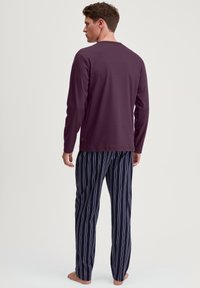 Camicia a maniche lunghe color bordeaux abbinata a pantaloni da pigiama a righe blu navy e bianche; tessuto morbido, vestibilità rilassata e design semplice senza decorazioni.