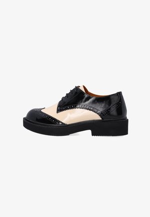 Schwarze und beige Leder Schuhe mit glänzender Oberfläche, Broguemuster, runder Zehenpartie und dicker schwarzer Sohle. Verfügt über Schnürsenkel und dekorative Muster.